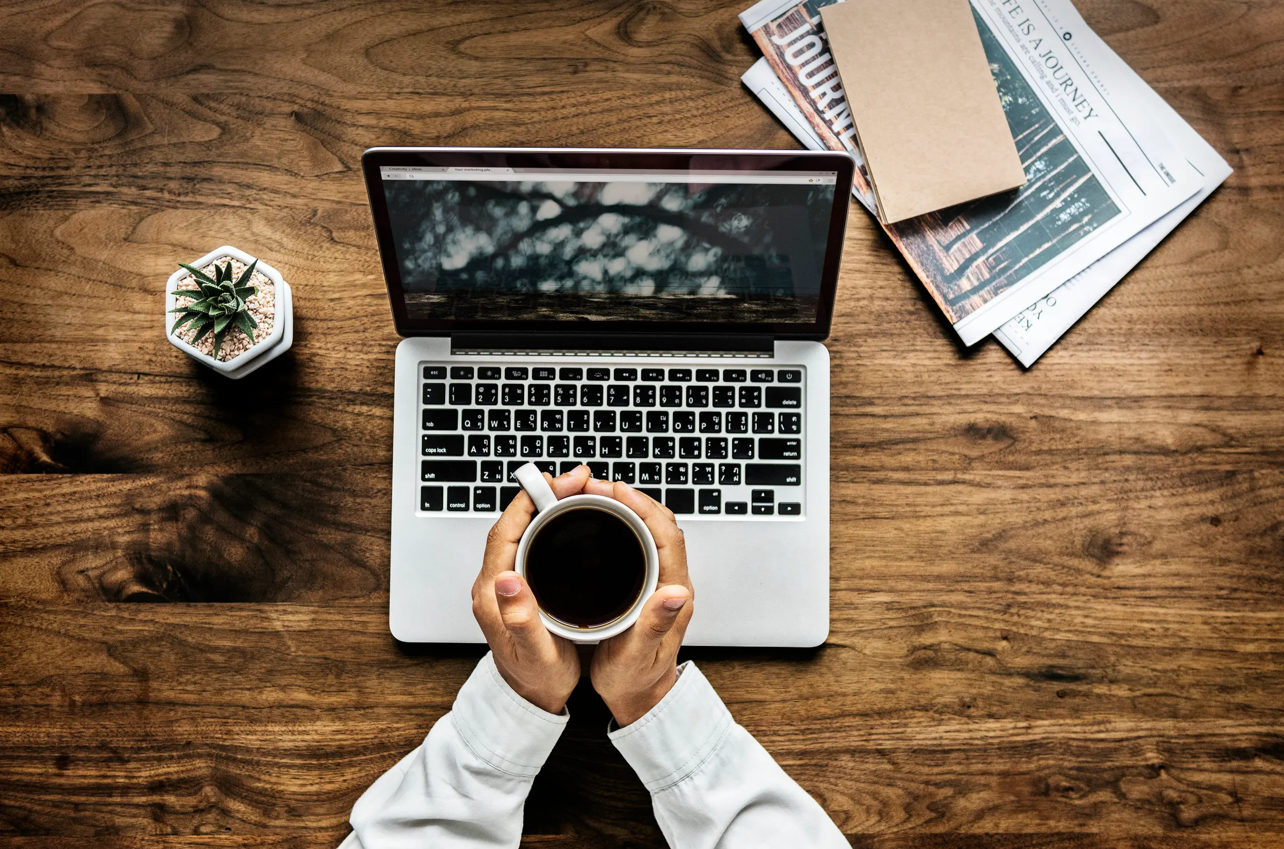 Aerial view of a man using a laptop on a wooden table