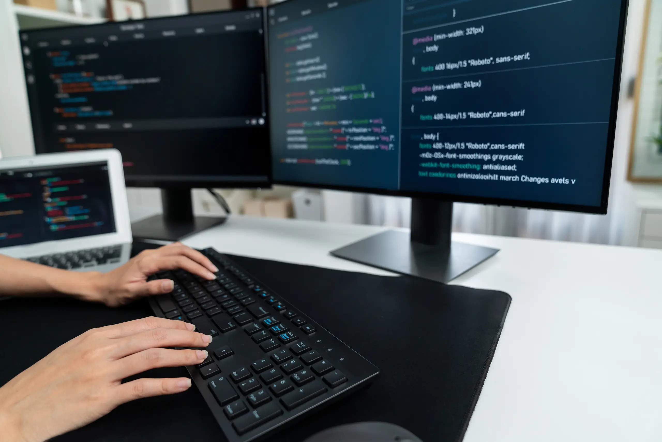 Hands typing code on a desktop keyboard