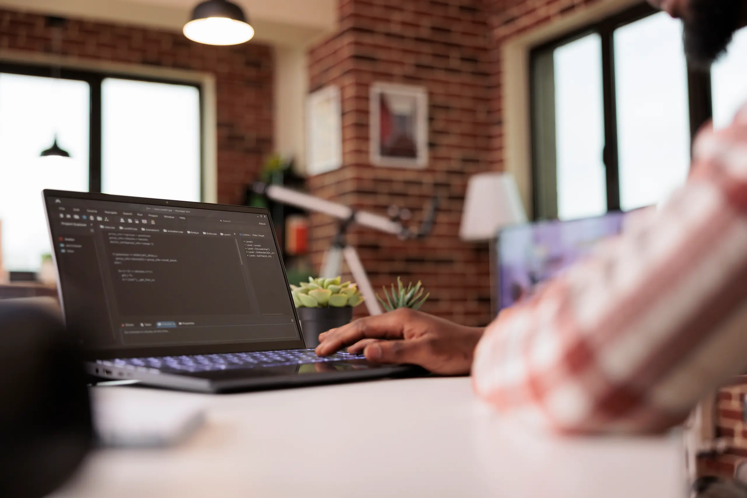 Developer with laptop and code on a screen in a brick room