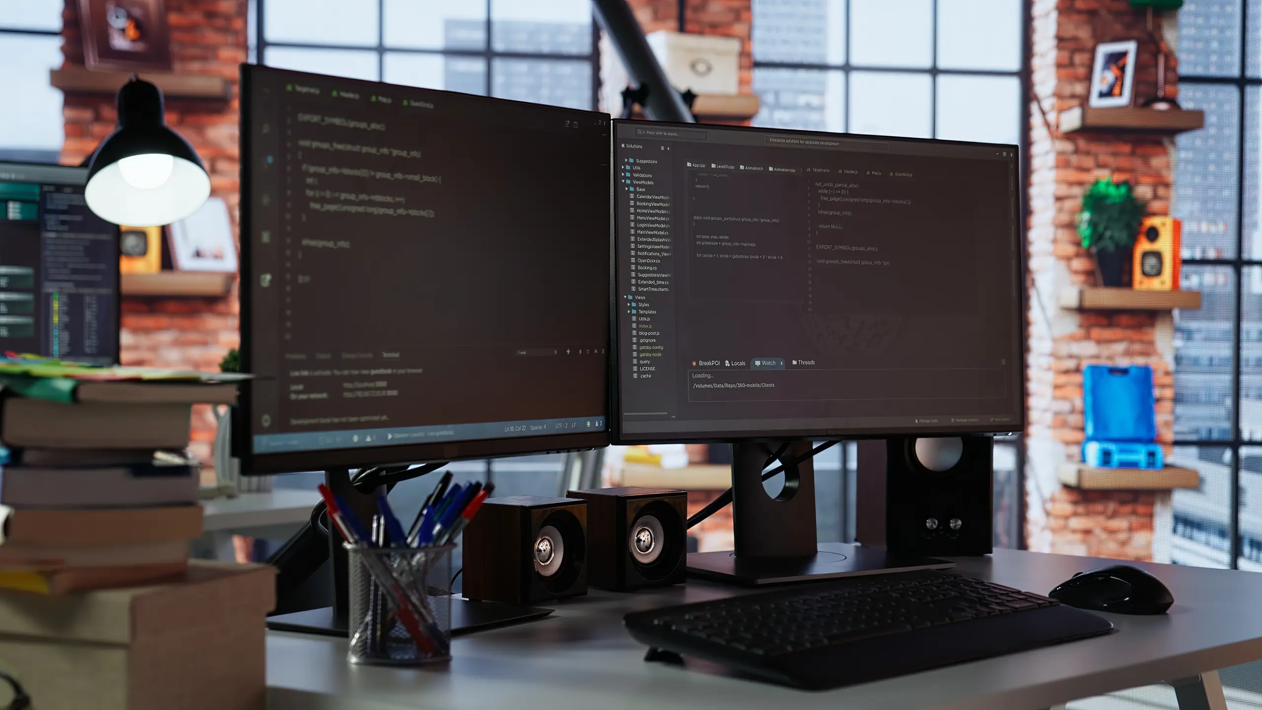 Dual monitor setup with code and speakers in a brick room