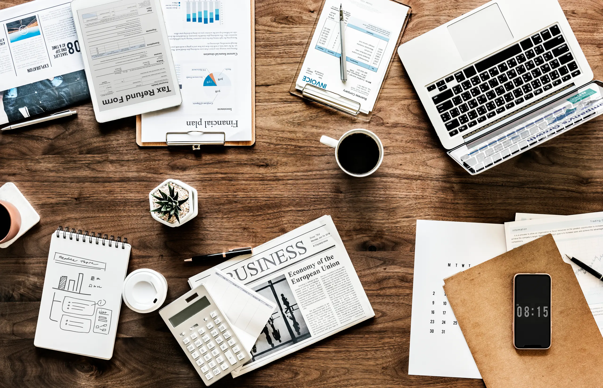 Flat lay of a desk with notebooks, charts, and a coffee cup