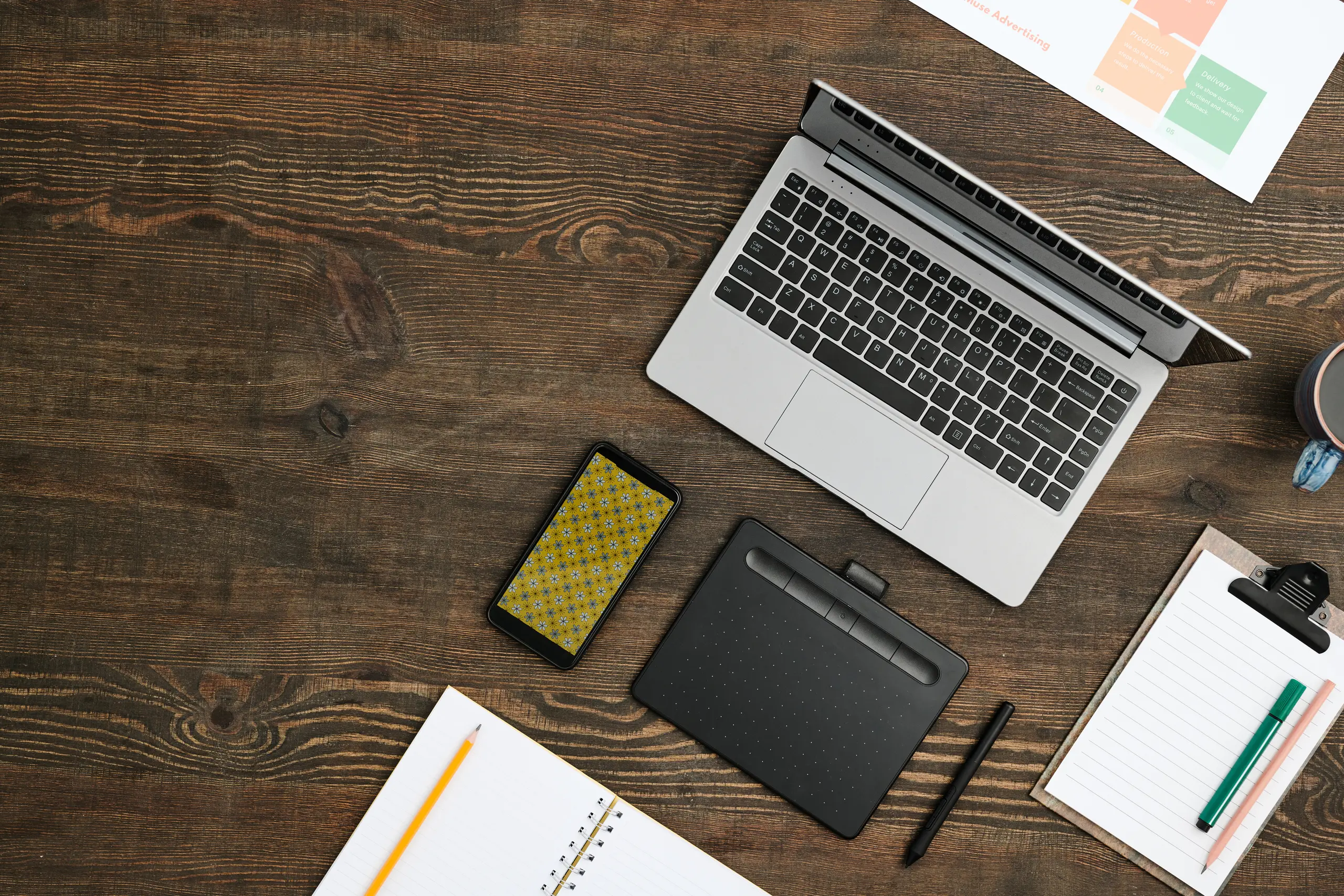 Flat lay of mobile gadgets, a drink, open notebook and pencil