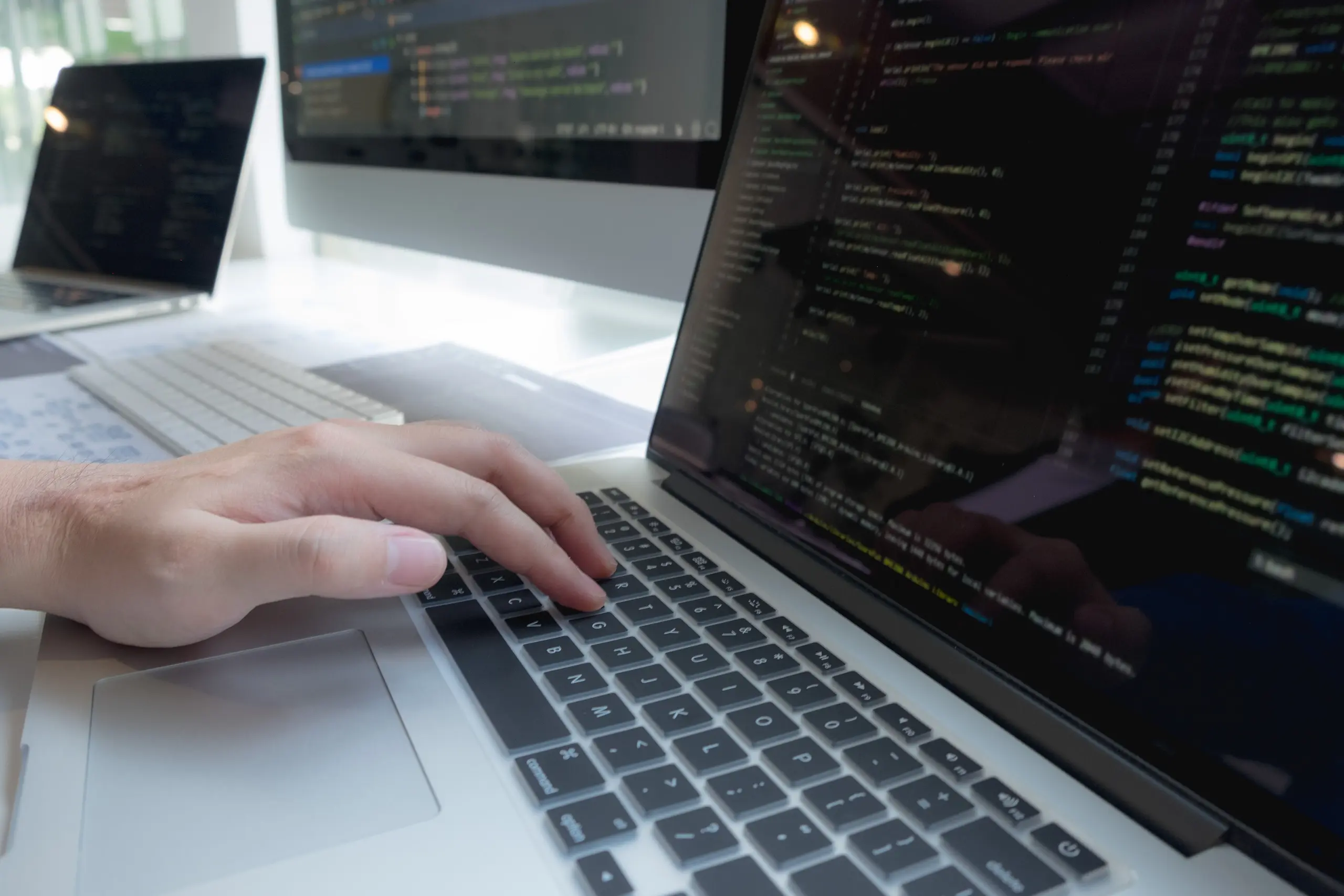 Hand close-up typing code on a laptop