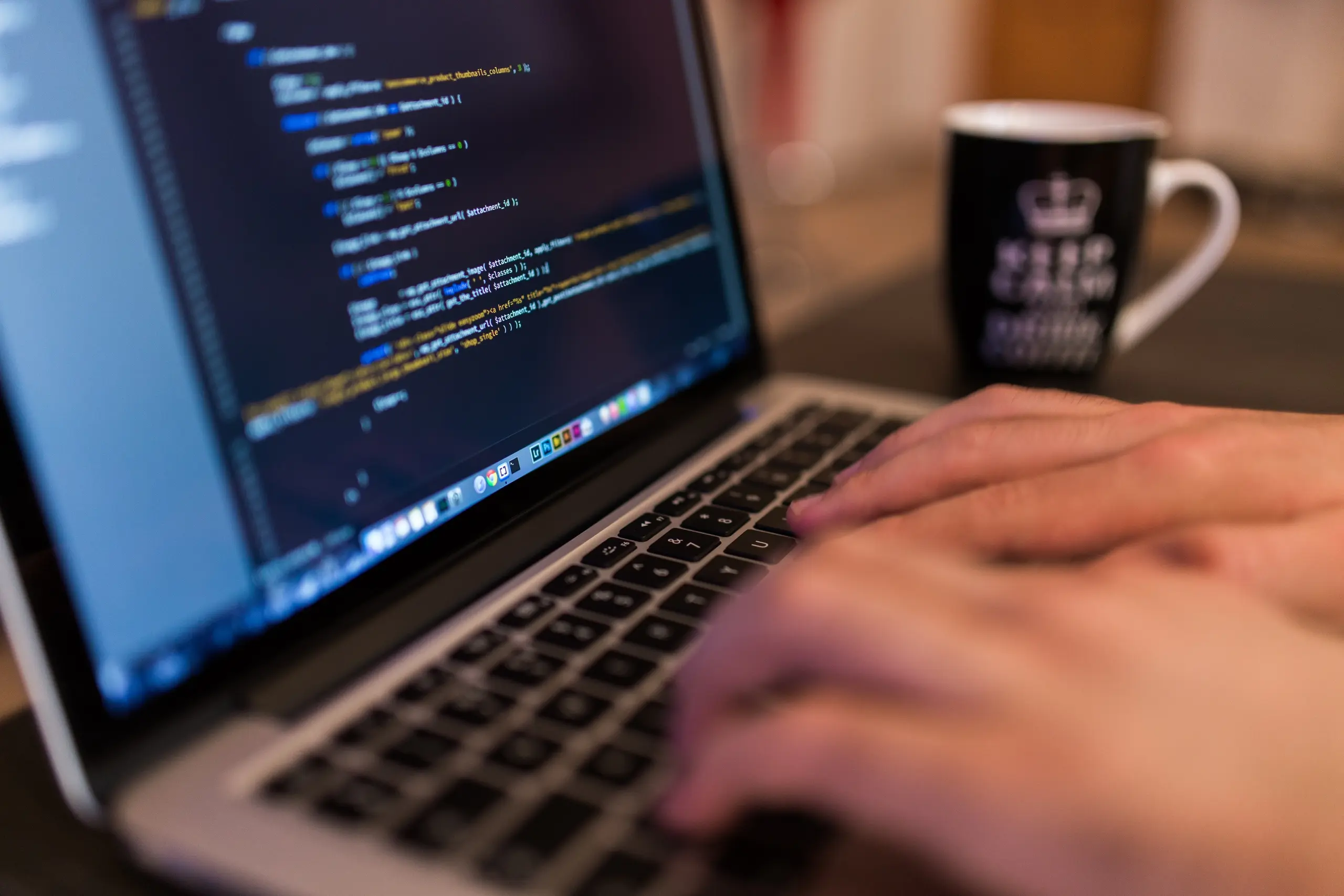 Close-up of hands typing on a laptop with a keep calm mug