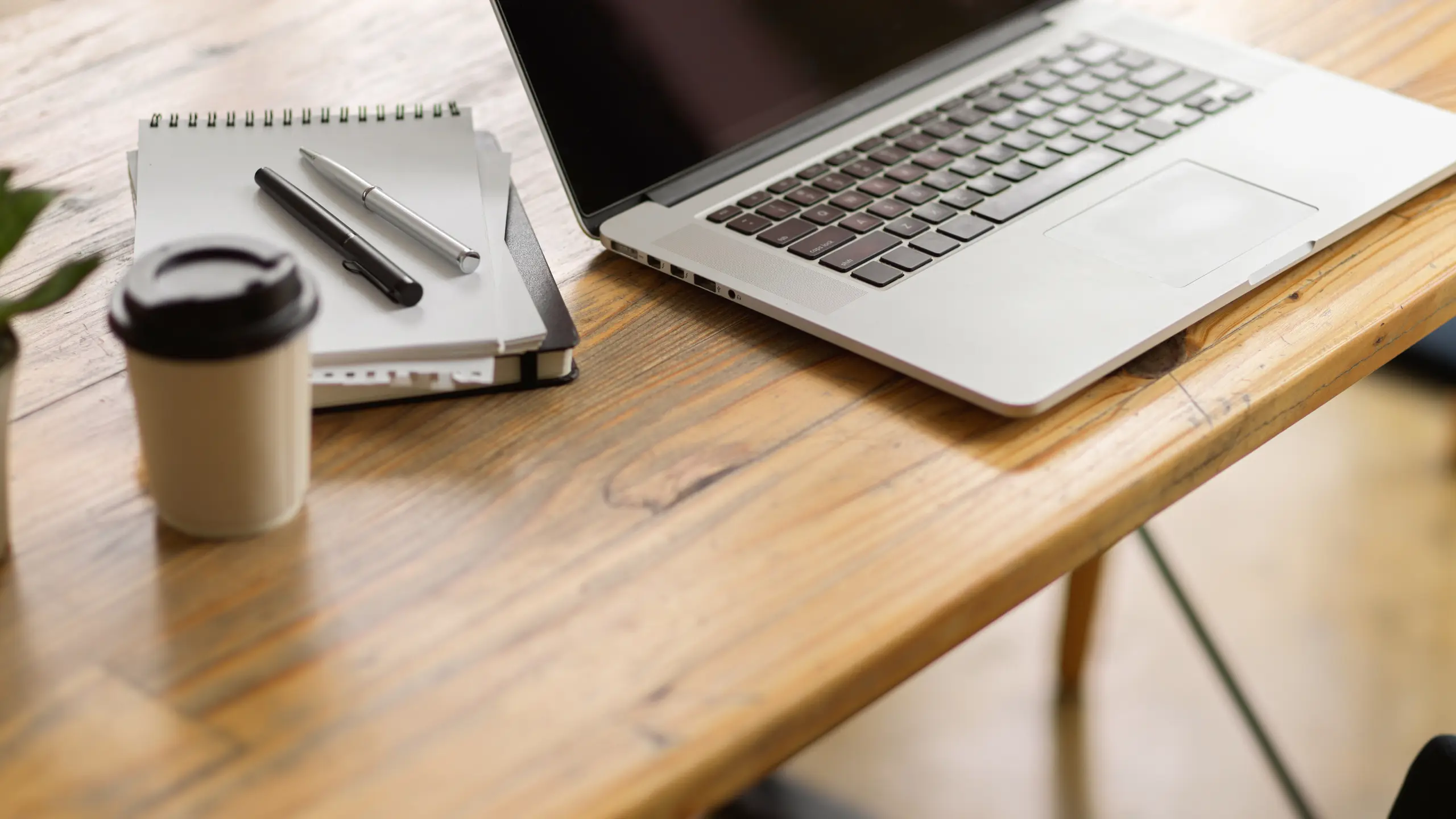 Laptop, notebook, coffee and pen on a desk