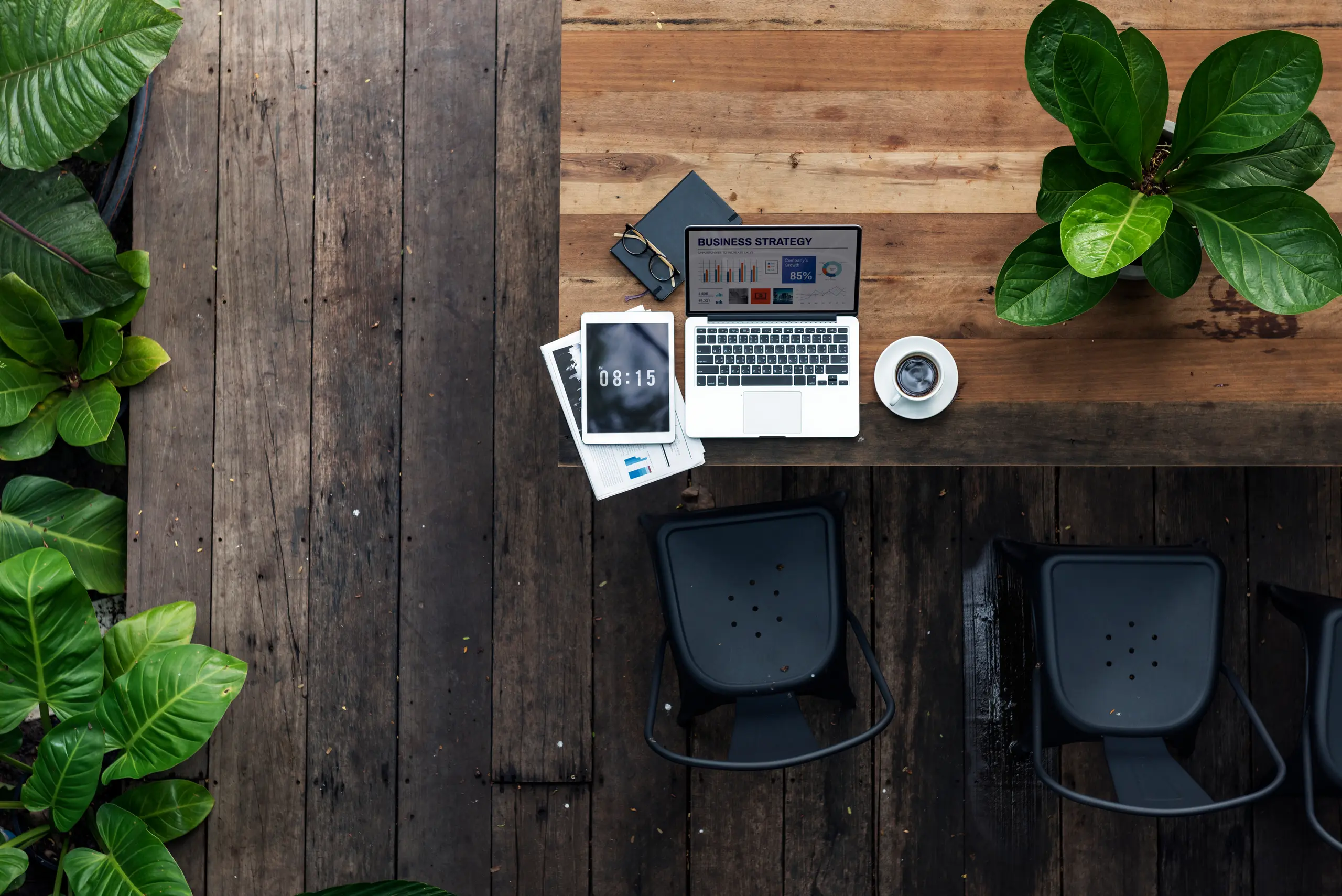 Laptop on a table with chairs and plants