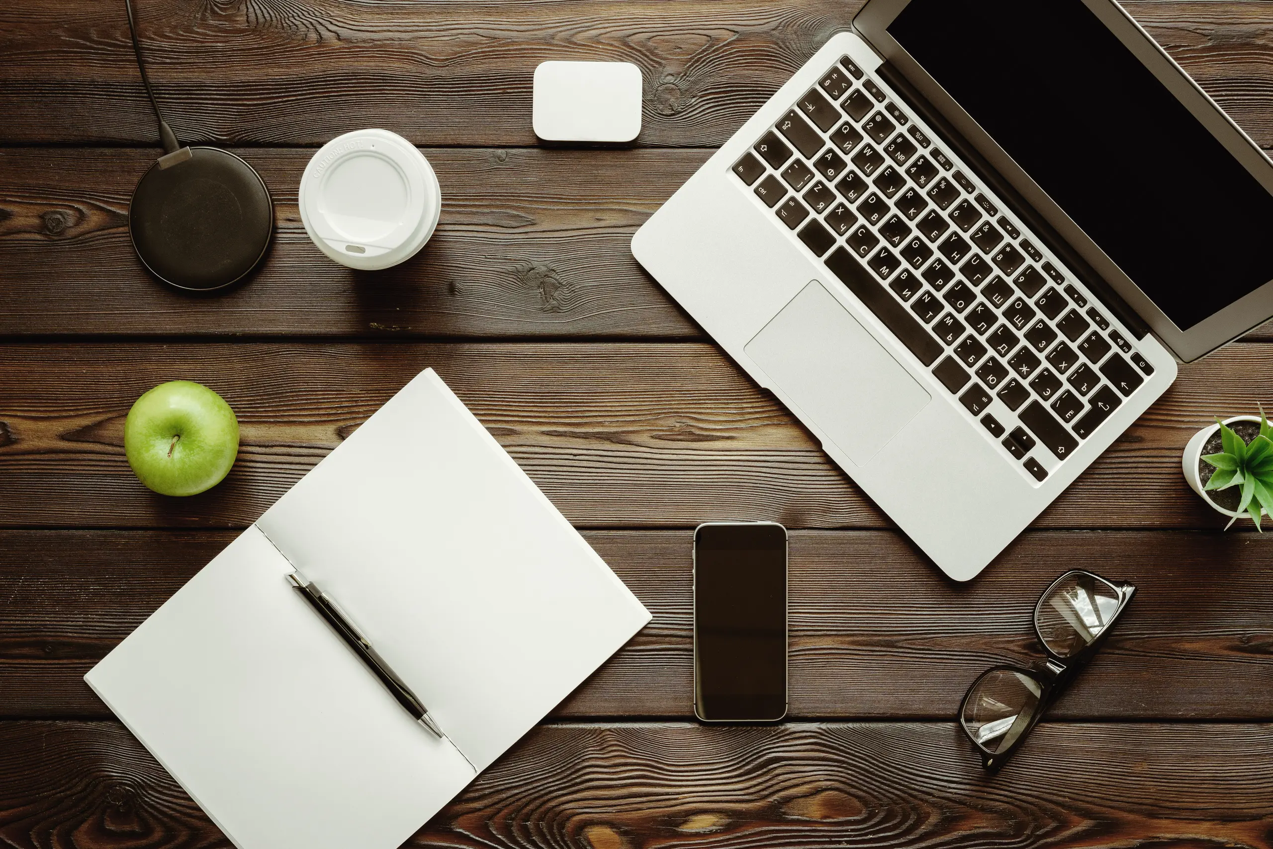 Office desk with laptop, supplies and a green apple