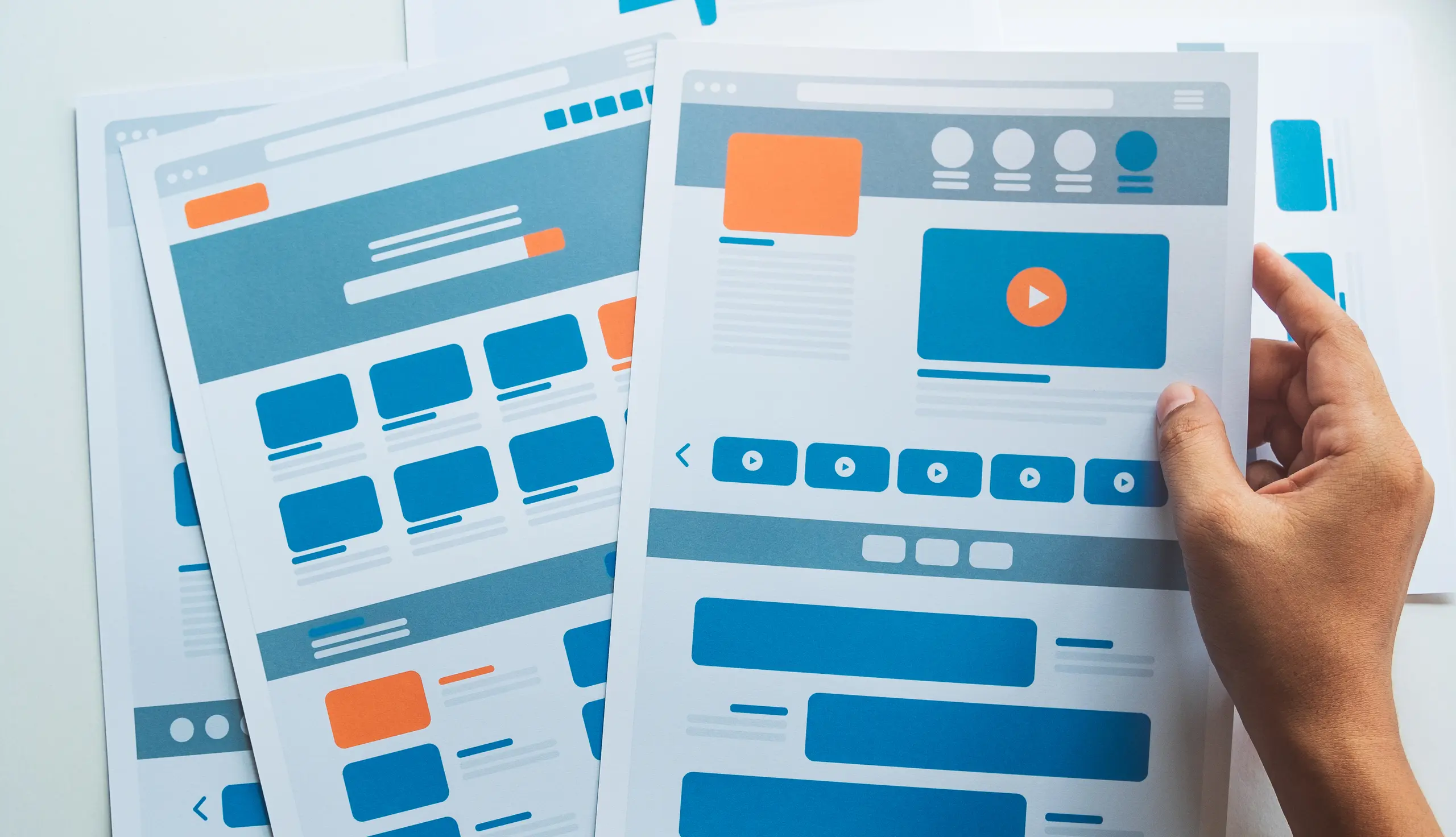 Person holding UI/UX design sheets